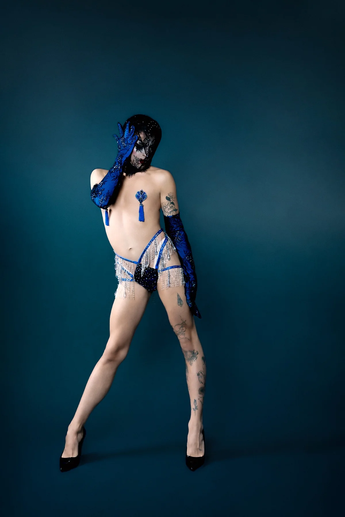 Artiste portant un costume burlesque bleu et argent sur mesure, avec gants longs et franges scintillantes, création Bonnippies.